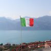 a flag flying on top of a hill next to a body of water